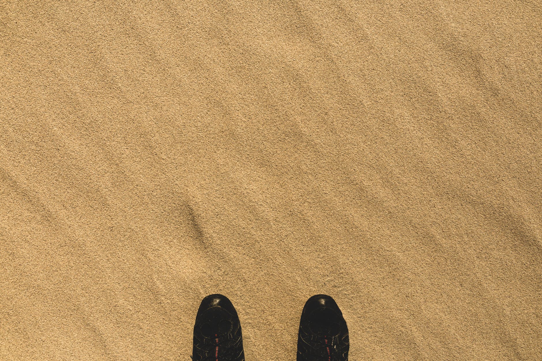 pair of black shoes on sand